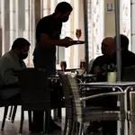 Un camarero atiende una mesa en una terraza 