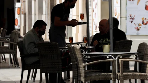 Un camarero atiende una mesa en una terraza