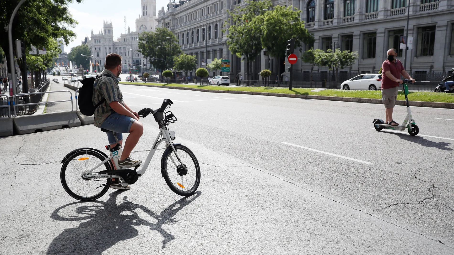 Una hombre transita la madrileña calle Alcalá con una bicicleta del servicio Bicimad
