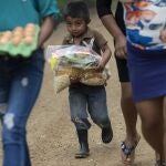A boy helps his family carry home food that, before the COVID-19 lockdown closed schools, was fed to students as they leave the school in Tizamarte, Wednesday, Dec. 9, 2020. Average monthly earnings here are less than the cost of the basket of basic goods. (AP Photo/Moises Castillo)