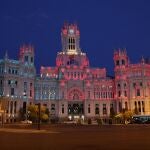 La fachada del Palacio de Cibeles, sede del Ayuntamiento de Madrid, iluminada con los colores de las banderas de España y Portugal