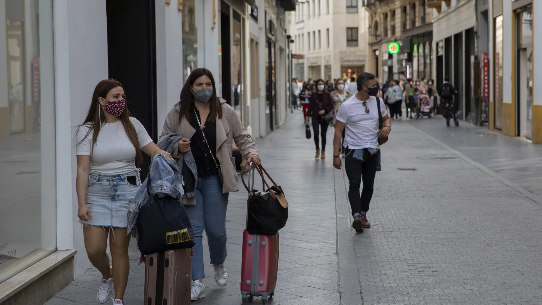 Viandantes con mascarilla por una calle comercial de Sevilla