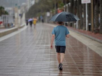 Un hombre camina bajo la lluvia por el Paseo Maritimo de Almería. EFE / Carlos Barba