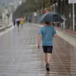Un hombre camina bajo la lluvia por el Paseo Maritimo de Almería. EFE / Carlos Barba