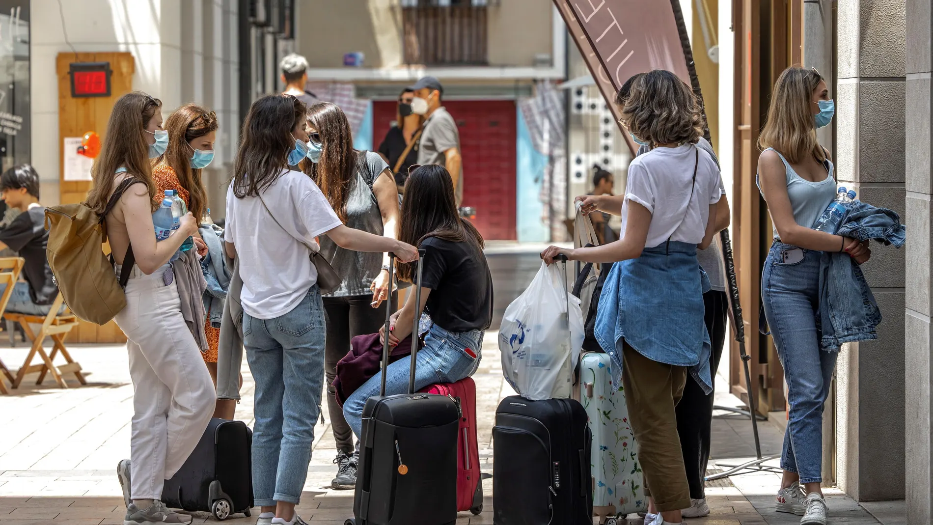 Varias turistas esperan junto a sus maletas frente al portal de un edificio del centro histórico de Valencia