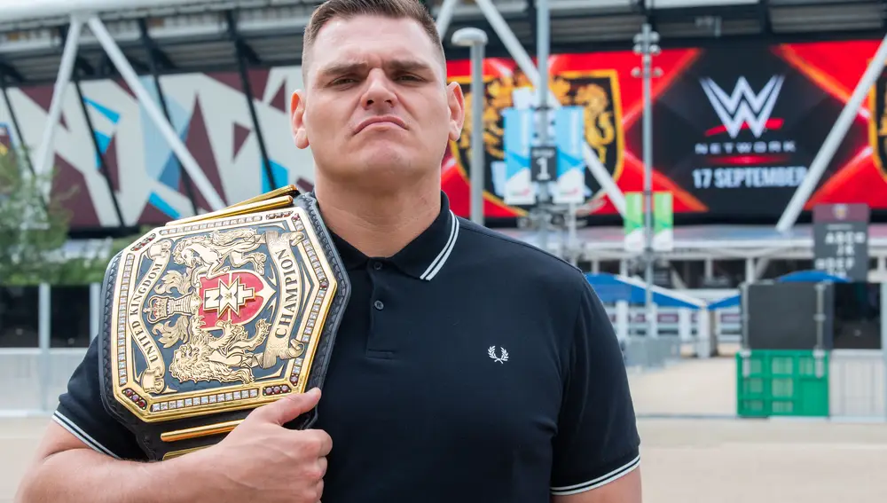 Walter, a las afueras de un estadio británico, junto al cinturón que le acredita como campeón de NXT UK