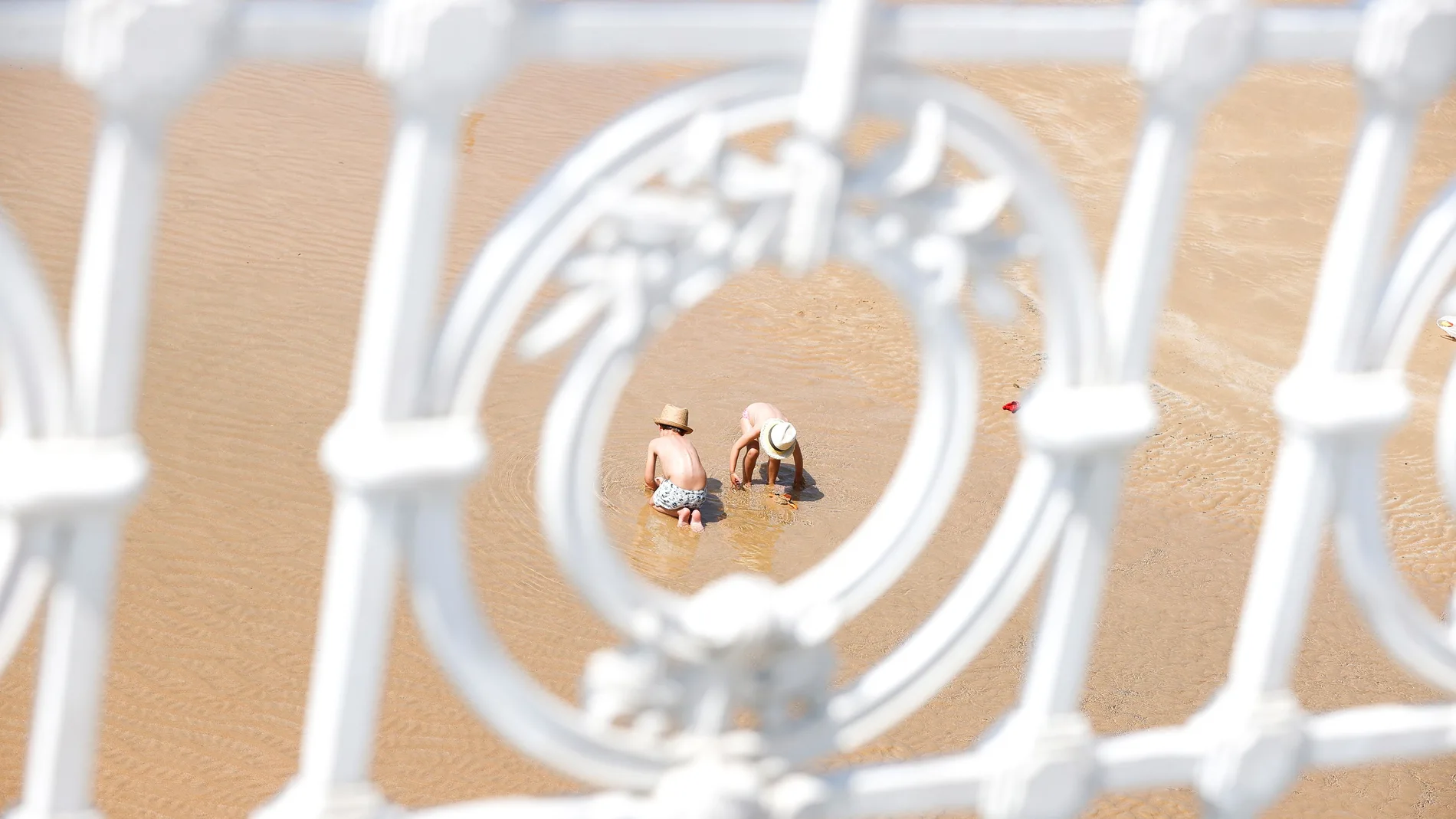 Dos niños juegan solos en la playa de La Concha de San Sebastián