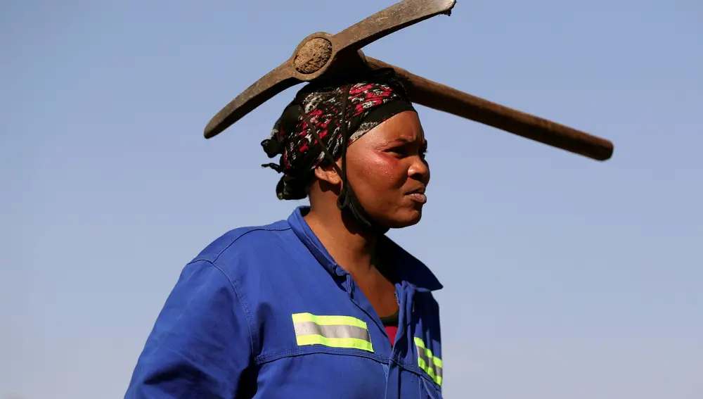 Una mujer con un pico en la cabeza busca diamantes en la aldea surafricana