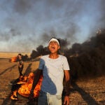 Un palestino junto neumáticos ardiendo junto a la frontera con Israel