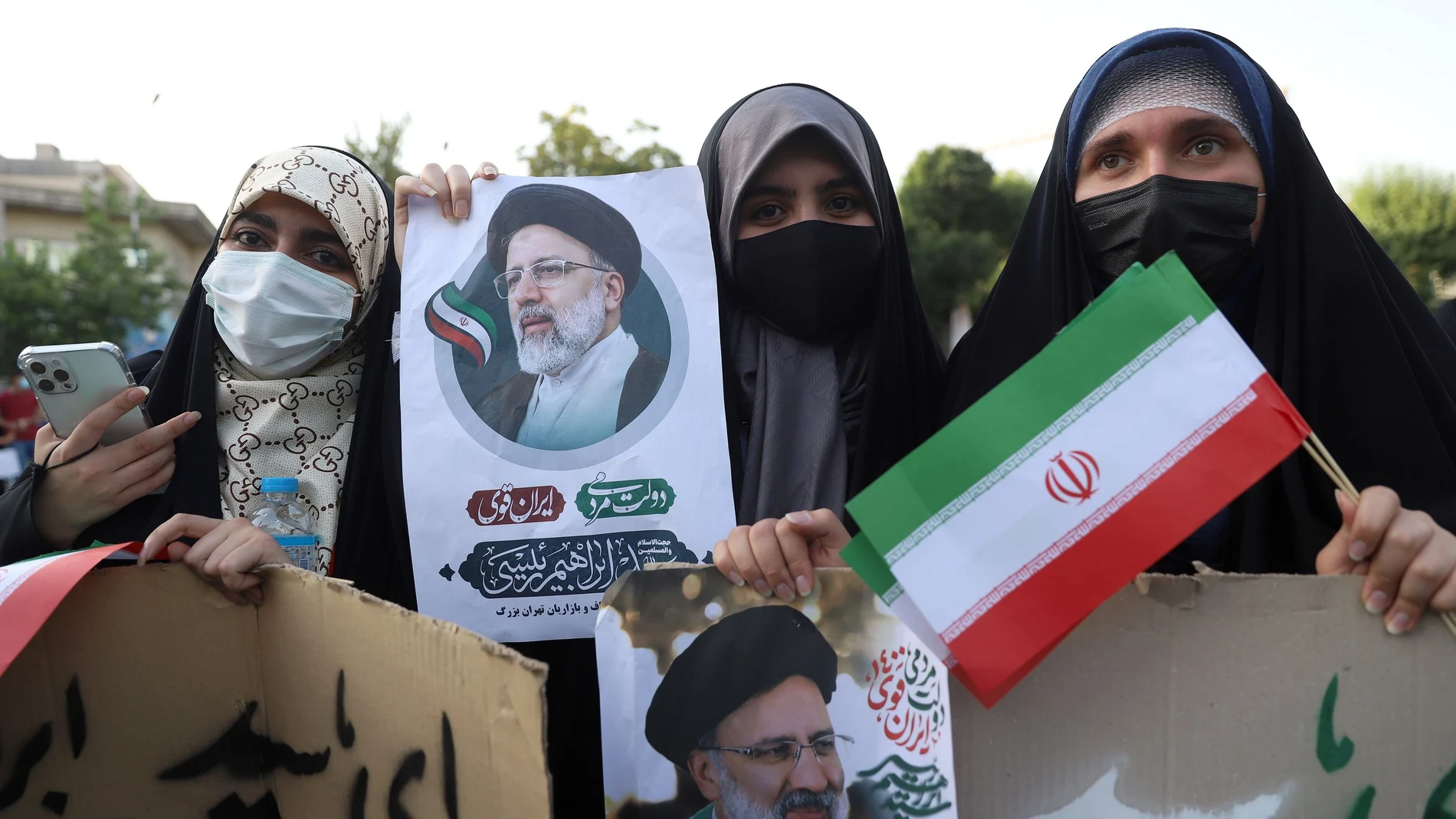 Seguidoras de Ebrahim Raisi sostienen posters de este en Irán. REUTERS