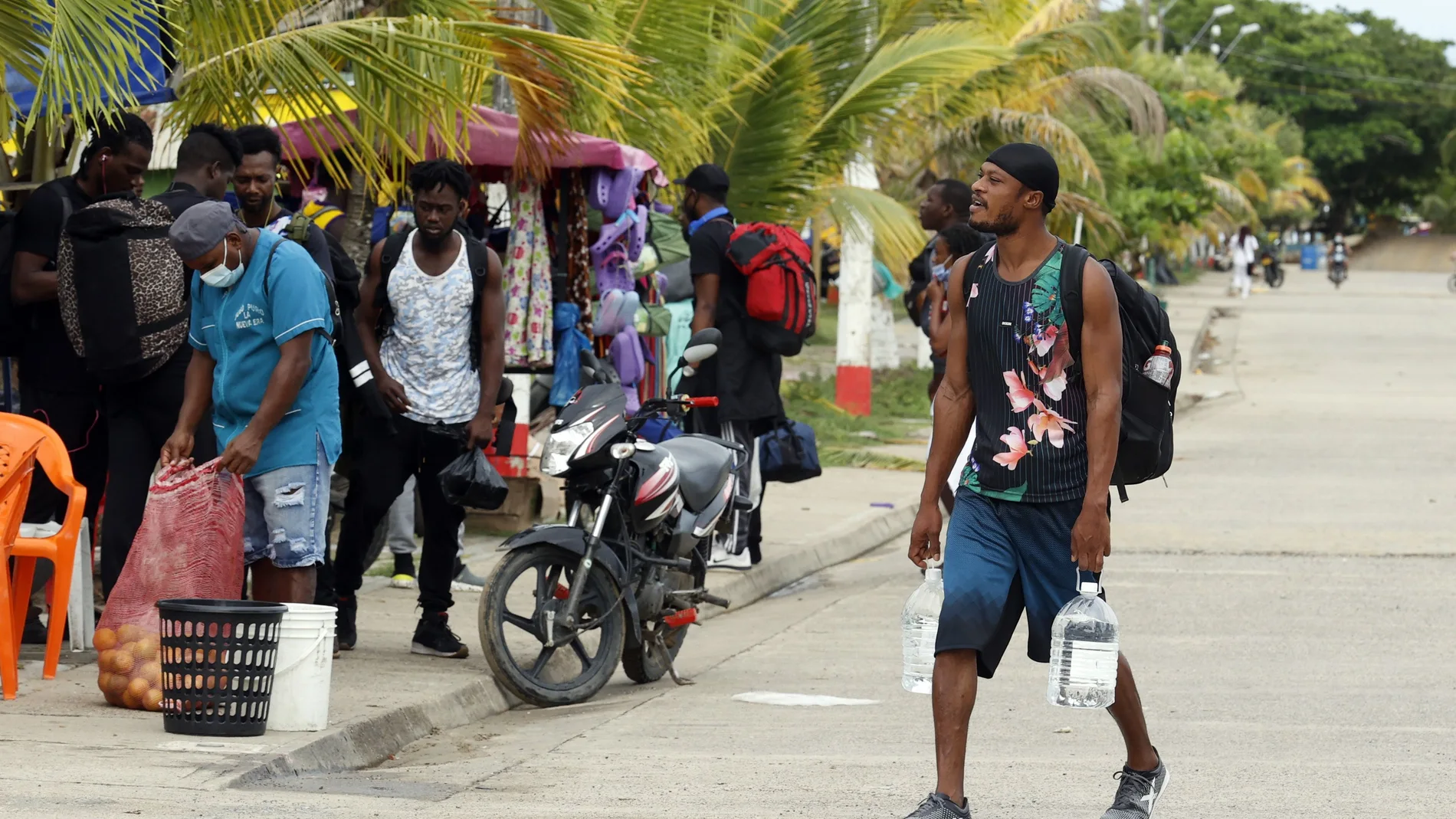 Migrantes de diversas partes del mundo caminan por una calle el 3 de mayo de 2021, cerca del embarcadero de Necoclí (Colombia).