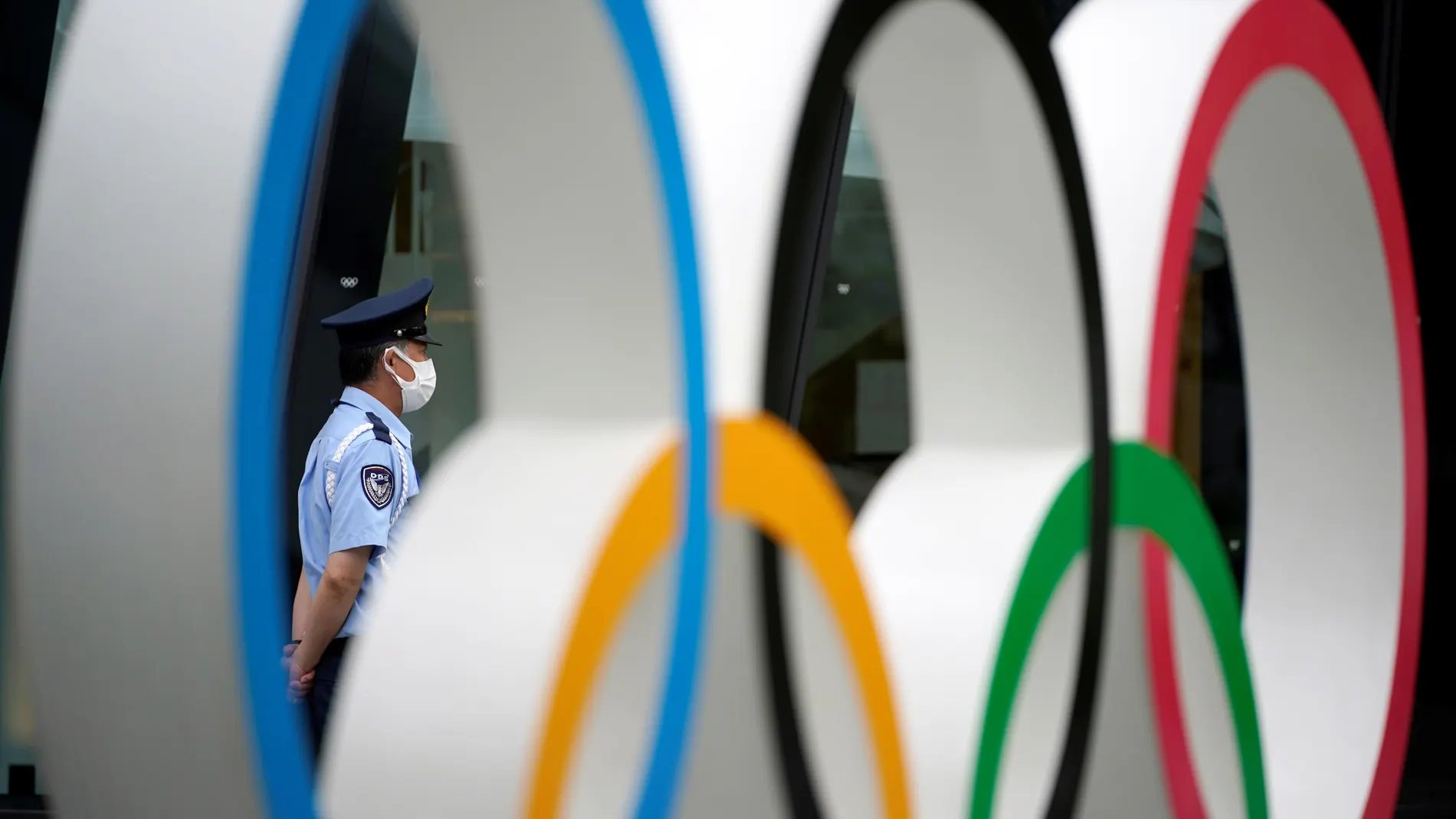 Un guardia de seguridad detrás del monumento de los anillos olímpicos, en las inmediaciones del estadio olímpico de Tokio. Los Juegos Olímpicos, que comenzarán el 23 de julio de 2021, fueron pospuestos un año a causa de la pandemia de la covid-19.