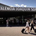 Dos personas transportan sus maletas a la salida de la estación de tren Joaquín Sorolla de València