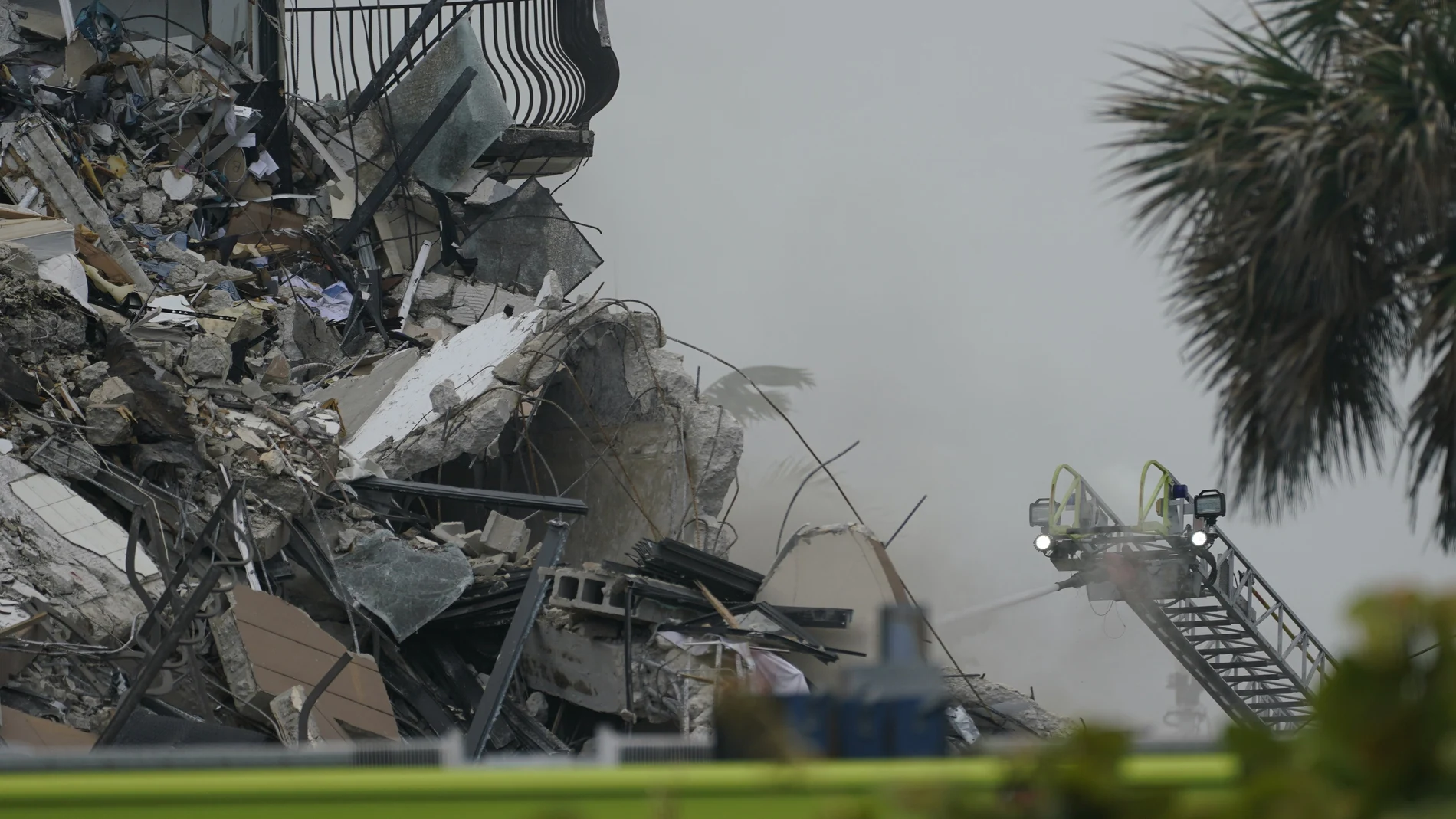 Firefighters use a ladder hose as smoke comes out of the rubble of a partially collapsed building, Thursday, June 24, 2021, in Surfside, Fla. (AP Photo/Wilfredo Lee)