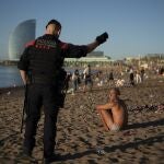 Un agente de los Mossos desalojando la playa de Barcelona