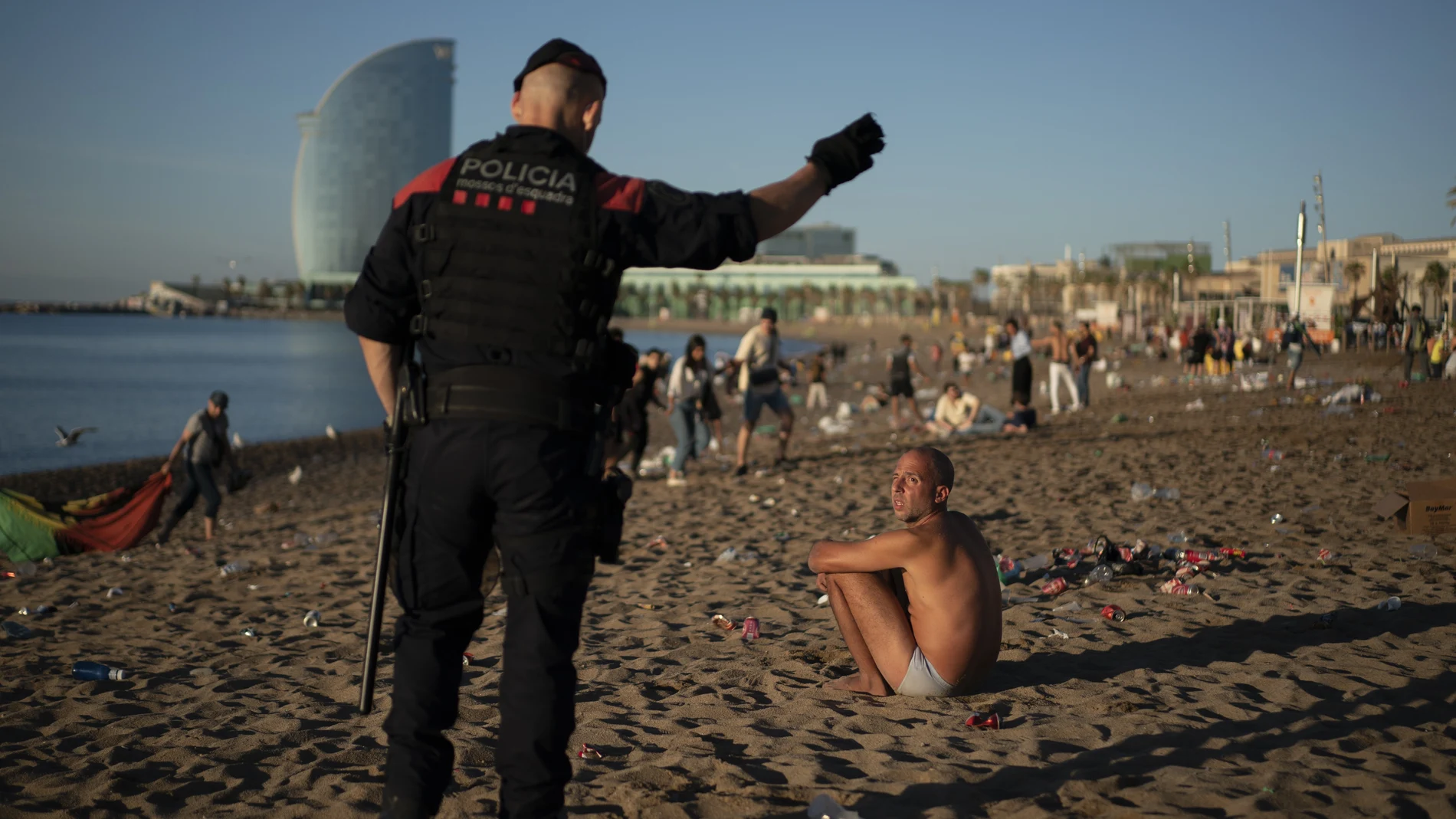 Un agente de los Mossos desalojando la playa de Barcelona