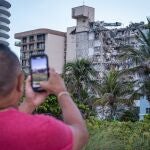 USA569. SURFSIDE (ESTADOS UNIDOS), 24/06/2021.- Un hombre toma una foto desde la playa a los destrozos y escombros del edificio de 12 pisos derrumbado parcialmente hoy, cerca de 88th Street y Collins Avenue, en la ciudad de Surfside, al norte de Miami Beach, Florida (EE.UU.). Entre las 99 personas desaparecidas que los socorristas buscan a contrarreloj tras derrumbarse la madrugada de este jueves un edificio de apartamentos en la localidad costera de Surfside, en Miami-Dade, figuran personas de Paraguay, Argentina y Chile, entre otros países de Latinoamérica. EFE/ Giorgio Viera