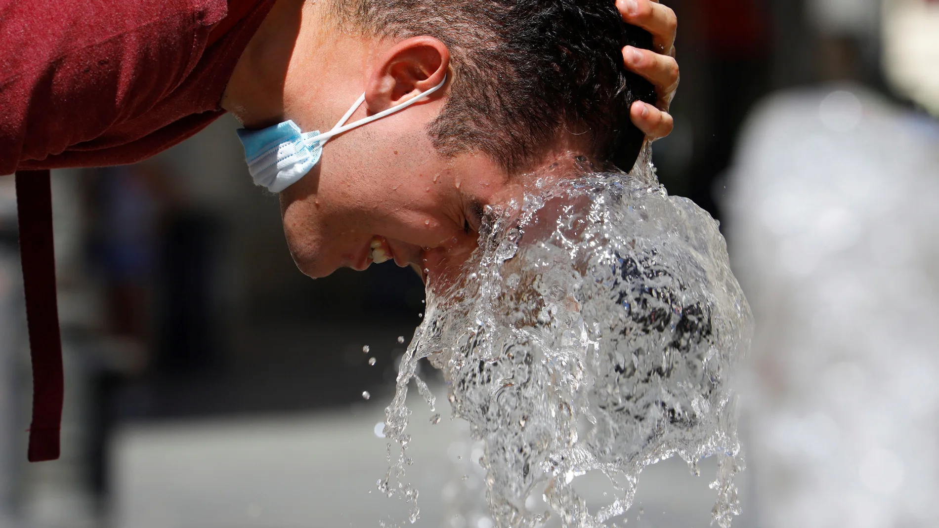 Una persona se refresca en una de la fuentes del centro de Córdoba