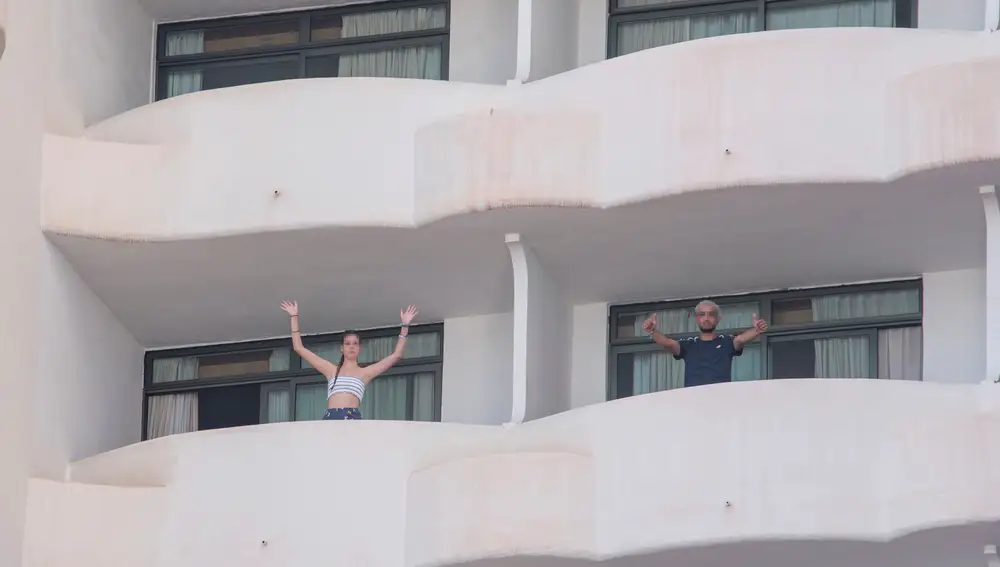 Dos jóvenes que permanecen en aislamiento en el hotel Palma Bellver de Palma saludan desde los balcones de sus habitacionesa