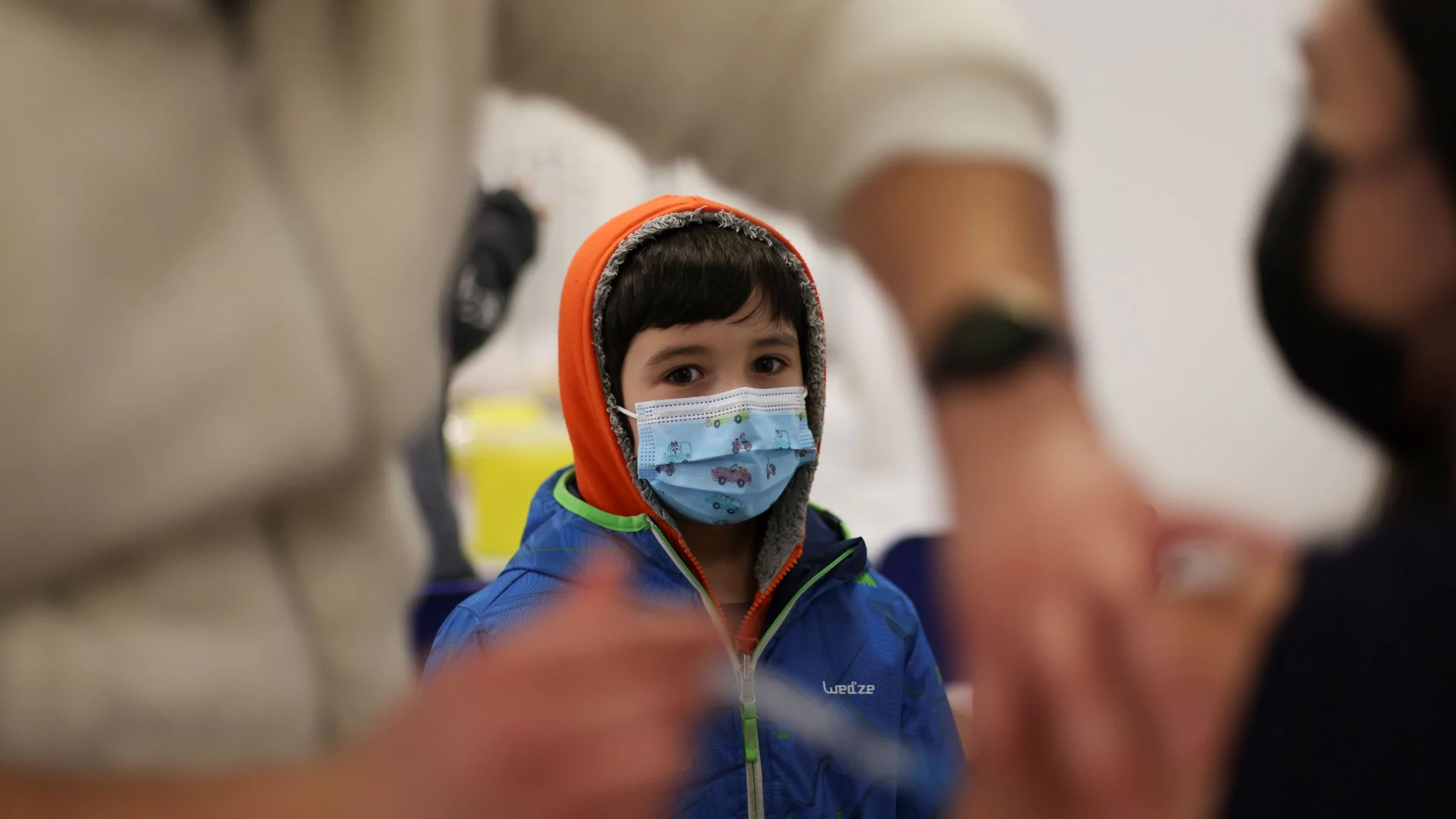 Un niño mira cómo inyectan una dosis de Pfizer a una mujer en Santiago de Chile