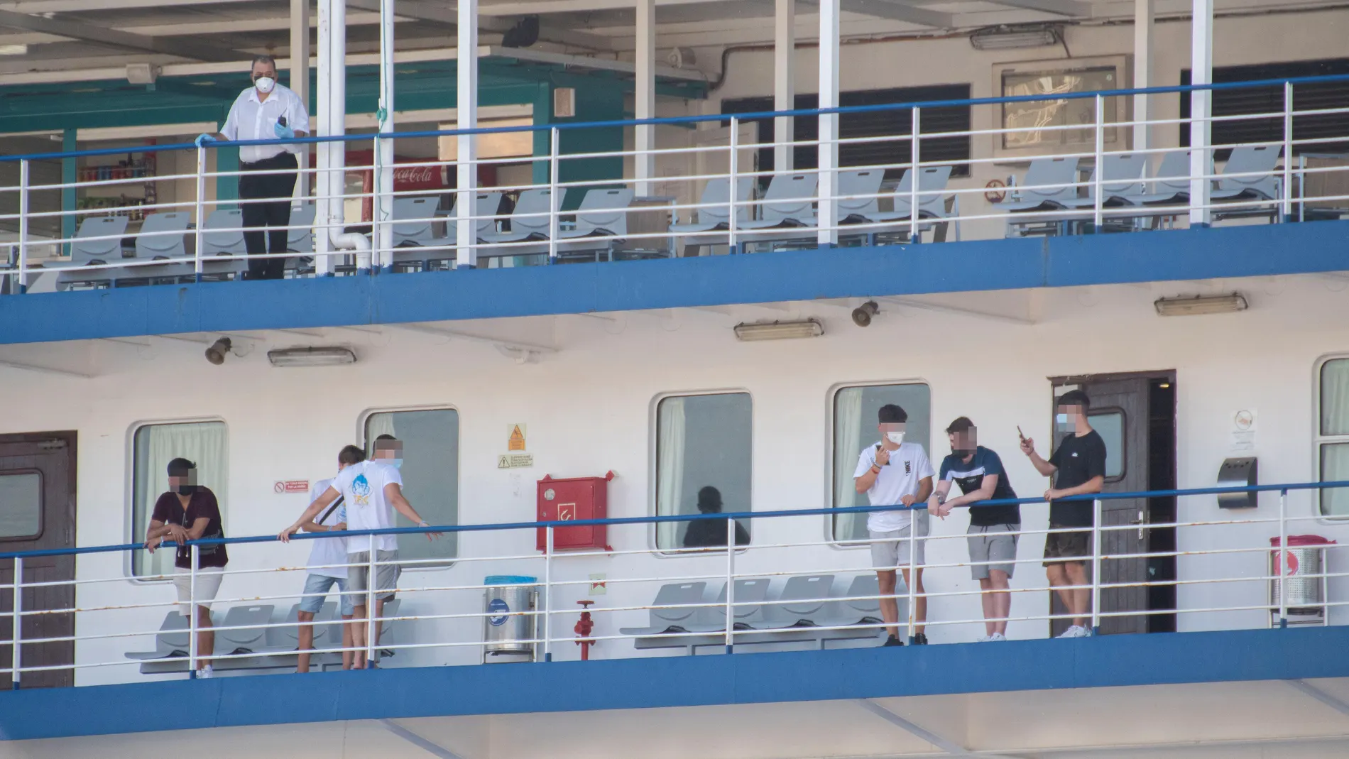 Varios estudiantes, que se encontraban en cuarentena por el macrobrote de covid-19, aguardan a bordo del "barco burbuja" su salida hacia Valencia, este jueves, en el puerto de Palma de Mallorca. EFE/Cati Cladera