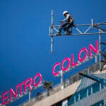 Imagen de unos operarios desmontando andamios en las Torres de Colón con la letras del edificio Centro Colon a la espalda