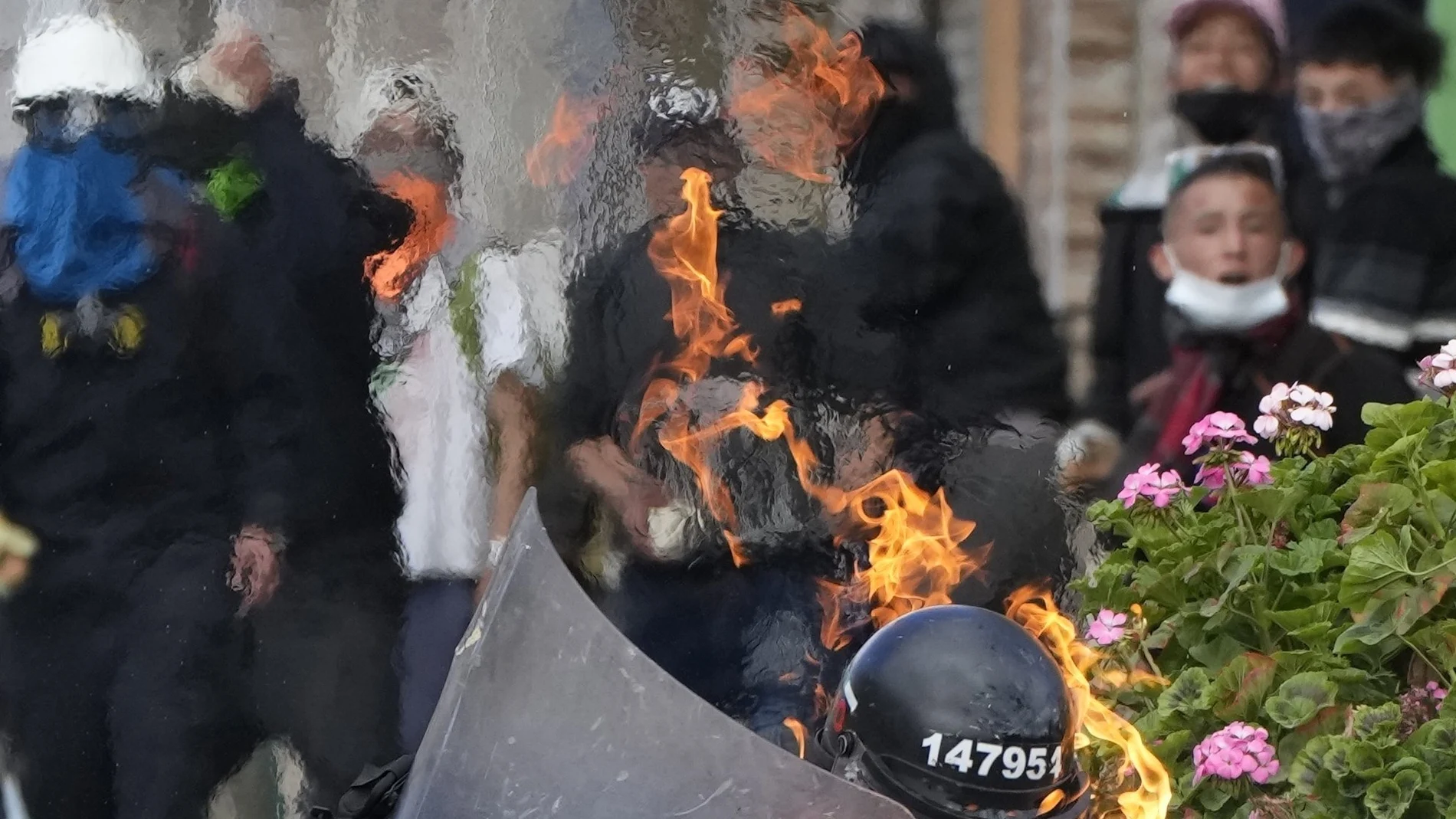 A police officer is engulfed in flames after he was hit with a petrol bomb during an anti-government protest triggered by proposed tax increases on public services, fuel, wages and pensions in Bogota, Colombia, Monday, June 28, 2021. (AP Photo/Fernando Vergara)
