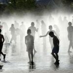 Un grupo de niños se refresca en una fuente de Madrid Río en una jornada marcada por las altas temperaturas en la capital de España.