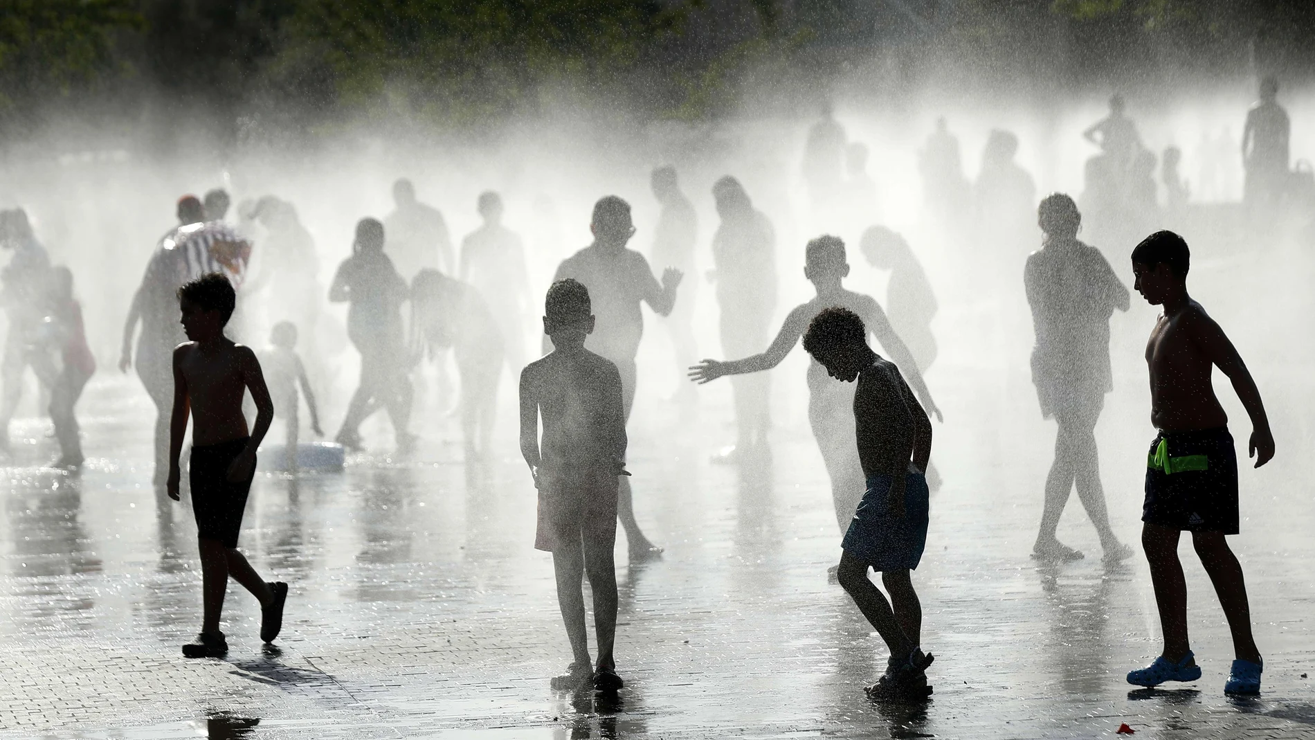 Un grupo de niños se refresca en una fuente de Madrid Río en una jornada marcada por las altas temperaturas en la capital de España.