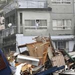 Un vecino mira por la ventana los daños causados por las fuertes lluvias en el distrito de Izusan, en Atami, Japón