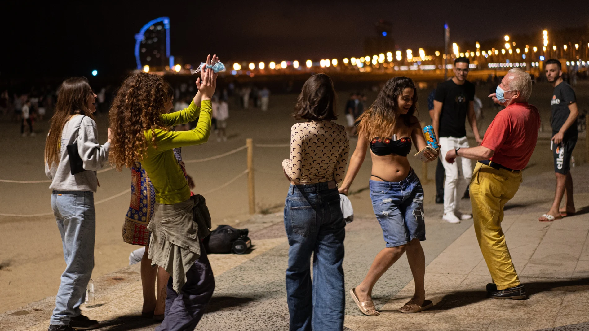Un grupo de chicas y un señor bailan a pié de playa en Barcelona, Catalunya.