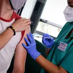 Una profesional sanitaria administra la vacuna contra la Covid-19 a un joven en Valencia