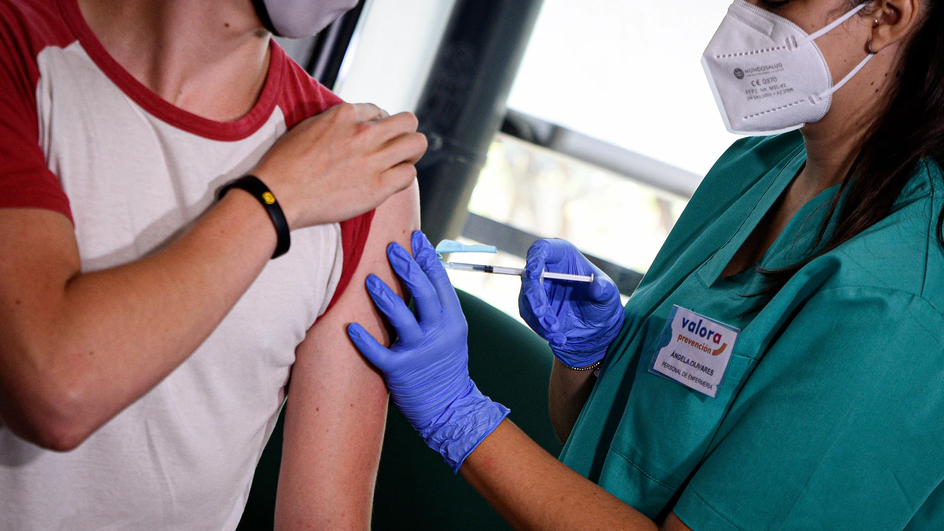 Una profesional sanitaria administra la vacuna contra la Covid-19 a un joven en Valencia