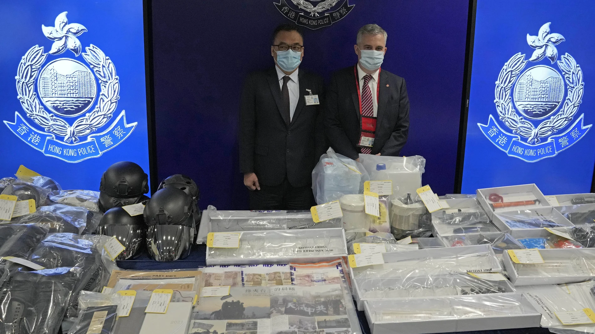 Senior Superintendent Li Kwai-wah, left, of Hong Kong Police National Security Department, and senior bomb disposal officer Alick McWhirter, right of Explosive Ordnance Disposal Bureau, pose with the confiscated evidence during a news conference as nine people were arrested over the alleged plot to plant bombs around Hong Kong, at the police headquarters in Hong Kong, Tuesday, July 6, 2021.(AP Photo/Kin Cheung)