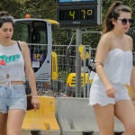 Dos mujeres pasan junto a un termómetro que marca 47º durante un día de alerta roja por altas temperaturas, a 12 de julio de 2021, en Valencia