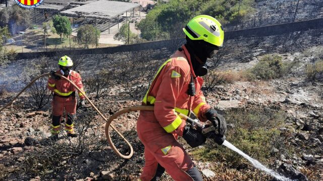 Bomberos trabajan en el incendio. Al fondo de la imagen se ve la proximidad del parque acuático
