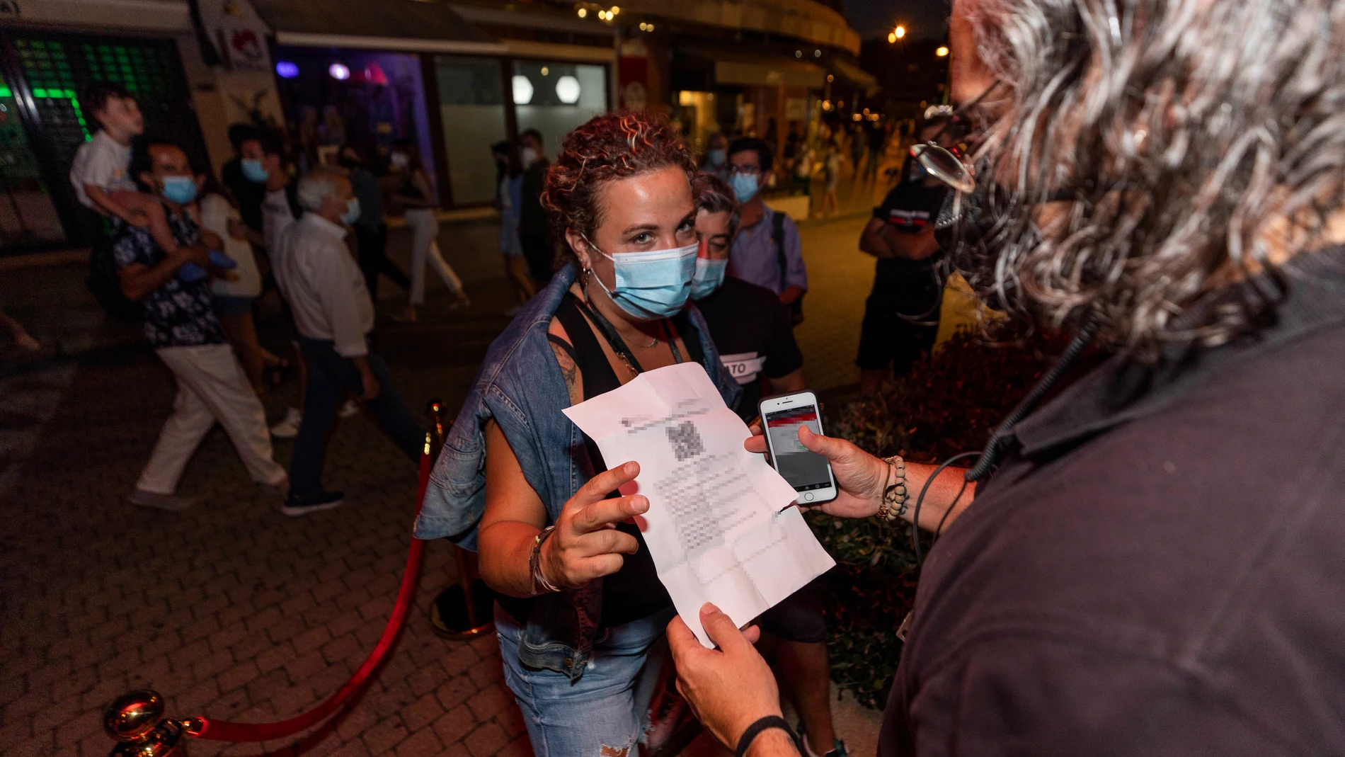 Una mujer muestra un certificado con sus vacunas contra el COVID-19 en regla para acceder a un local en Sansenxo, pasadas las 01:00 horas, a 17 de julio de 2021, en Pontevedra, Galicia (España). EP