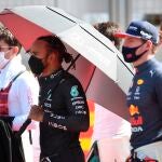 Lewis Hamilton, con paraguas, junto a Max Verstappen.