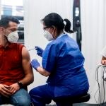 El joven de 31 años Oscar Parra, recibió esta tarde de la sanitaria Mercè Costa la vacuna número 500.000 en el centro de vacunación masivo de la Fira de Barcelona. EFE/Quique Garcia