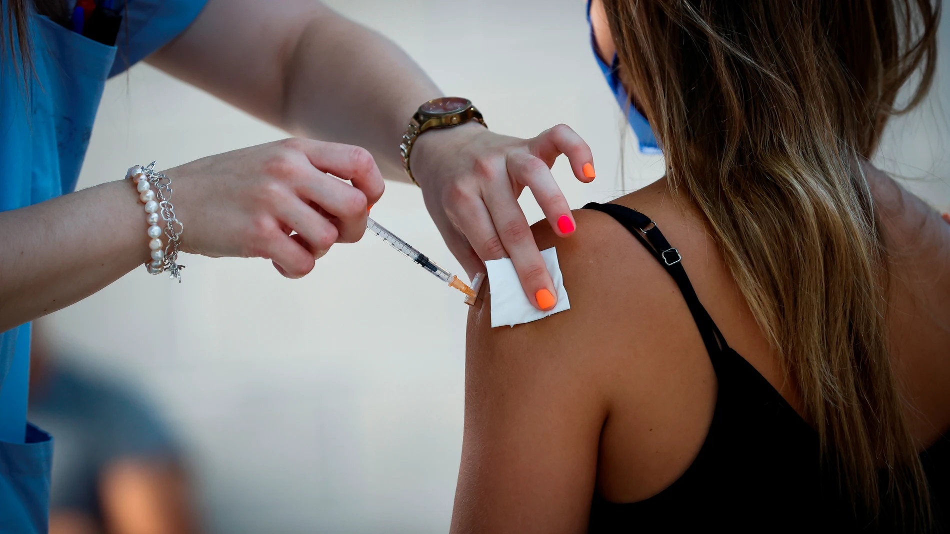 Una trabajadora sanitaria administra la vacuna contra la covid-19 a una joven