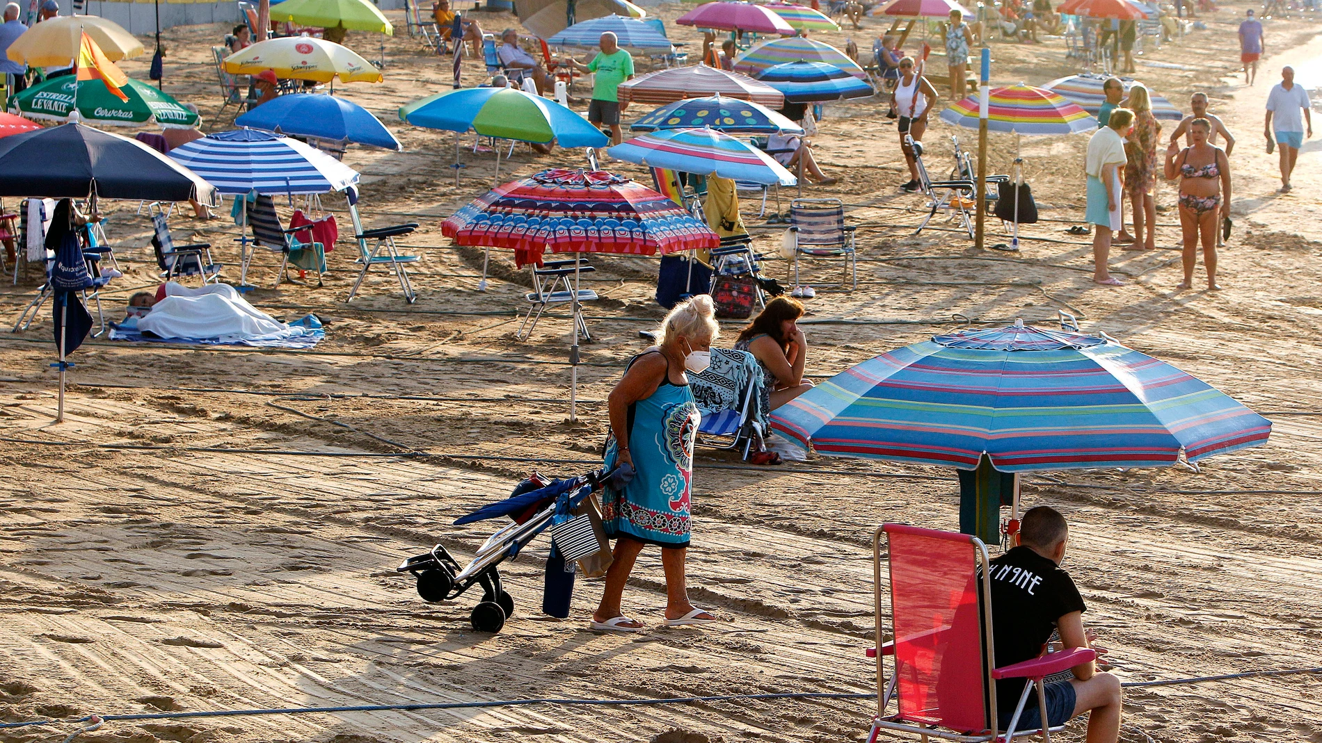 Una mujer se dispone a pasar un día en la playa del Cura de Torrevieja (Alicante)