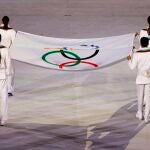 Operarios portan la Bandera Olímpica durante la ceremonia inaugural de los Juegos Olímpicos de Tokio 2020