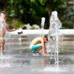 Dos niños juegan en una de las fuentes del Parque Central de Valéncia para mitigar el intenso calor.