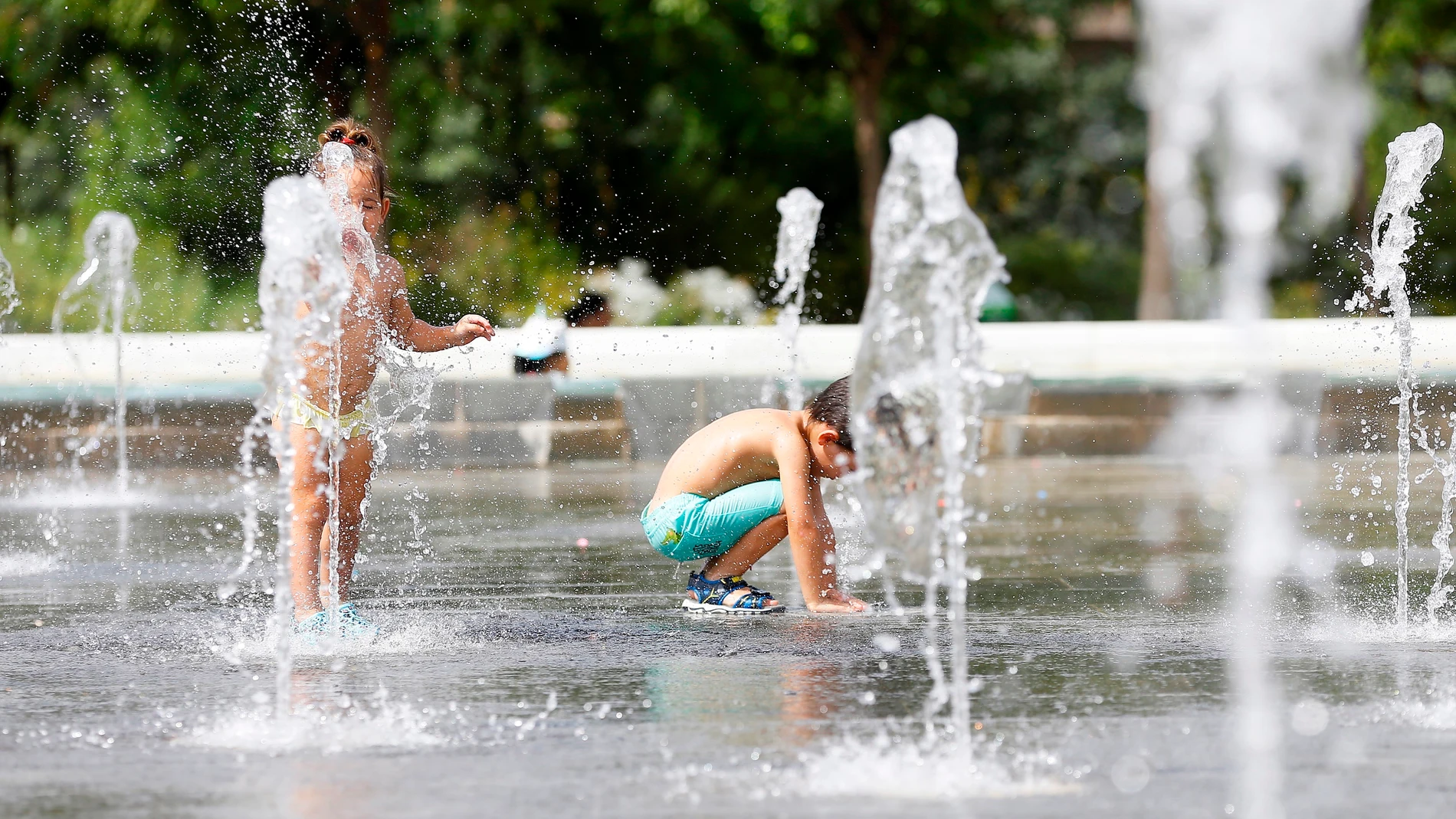 Dos niños juegan en una de las fuentes del Parque Central de Valéncia para mitigar el intenso calor.
