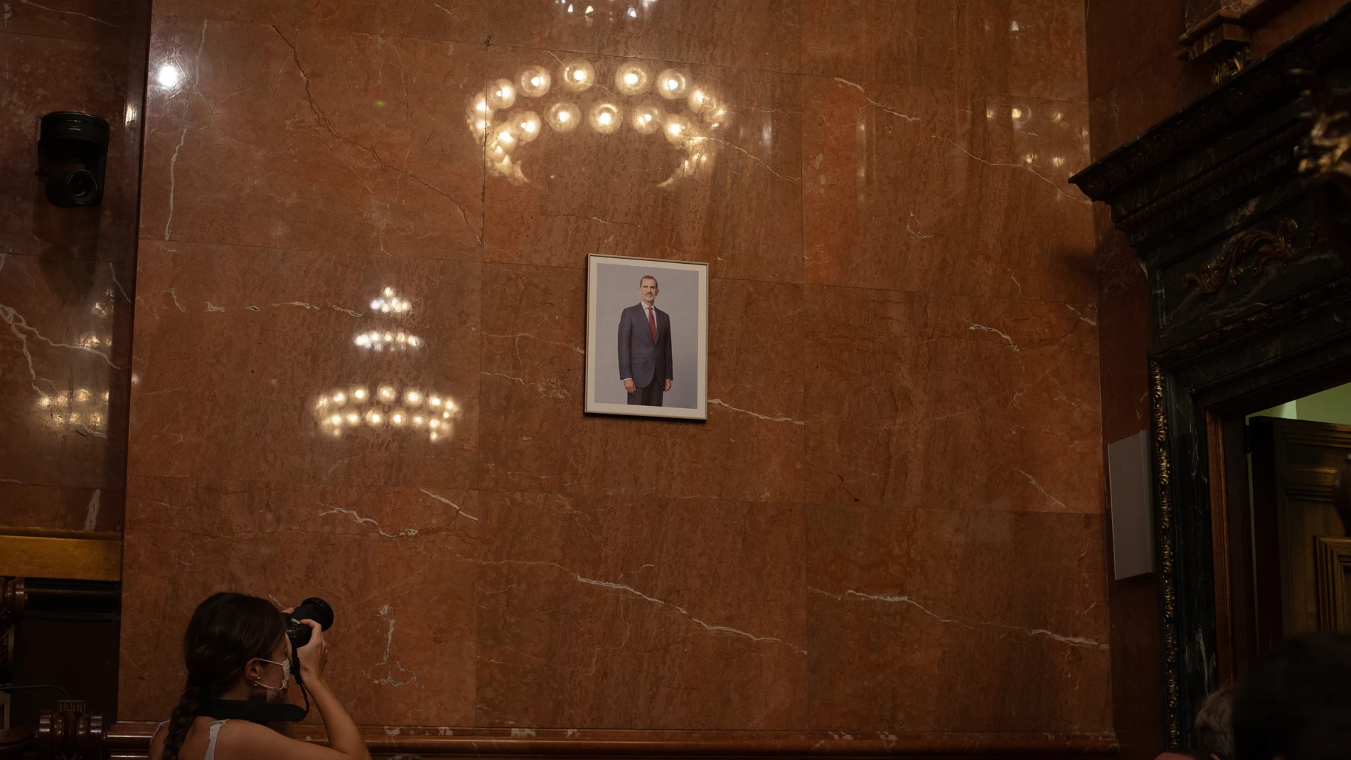 Una mujer fotografía la imagen del Rey colocada en la sala de plenos del Ayuntamiento de Barcelona
