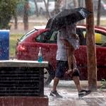 Un hombre protege con un paraguas a su hija de la lluvia en Ronda Sur, Murcia, el pasado lunes