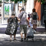 Una pareja de ancianos camina por la calle con un carro de compra, a 27 de julio de 2021, en Madrid, (España)
