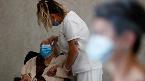 Una trabajadora sanitaria de una residencia de la Comunidad de Madrid atiende a Carmen, de 89 años
