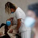 Una trabajadora sanitaria de una residencia de la Comunidad de Madrid atiende a Carmen, de 89 años