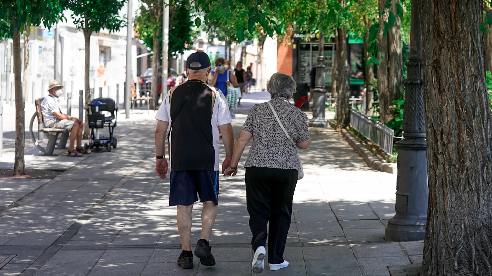 Una pareja de ancianos camina por la calle cogida de la mano, a 27 de julio de 2021, en Madrid, (España)